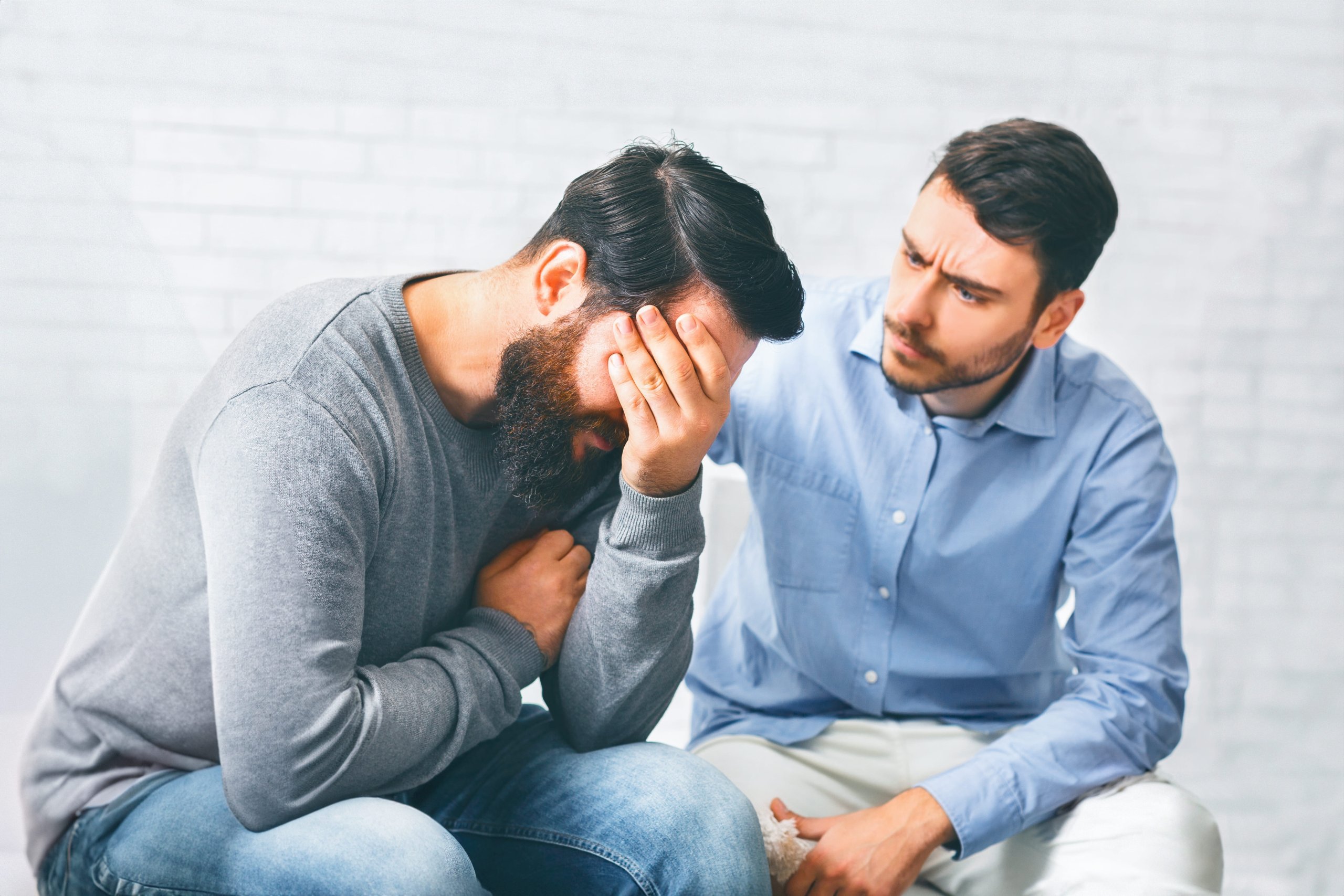 An upset man being comforted by a friend