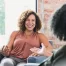 Two women talking during a mental health counseling session in a bright, sunlit therapy office in Orange County, California.